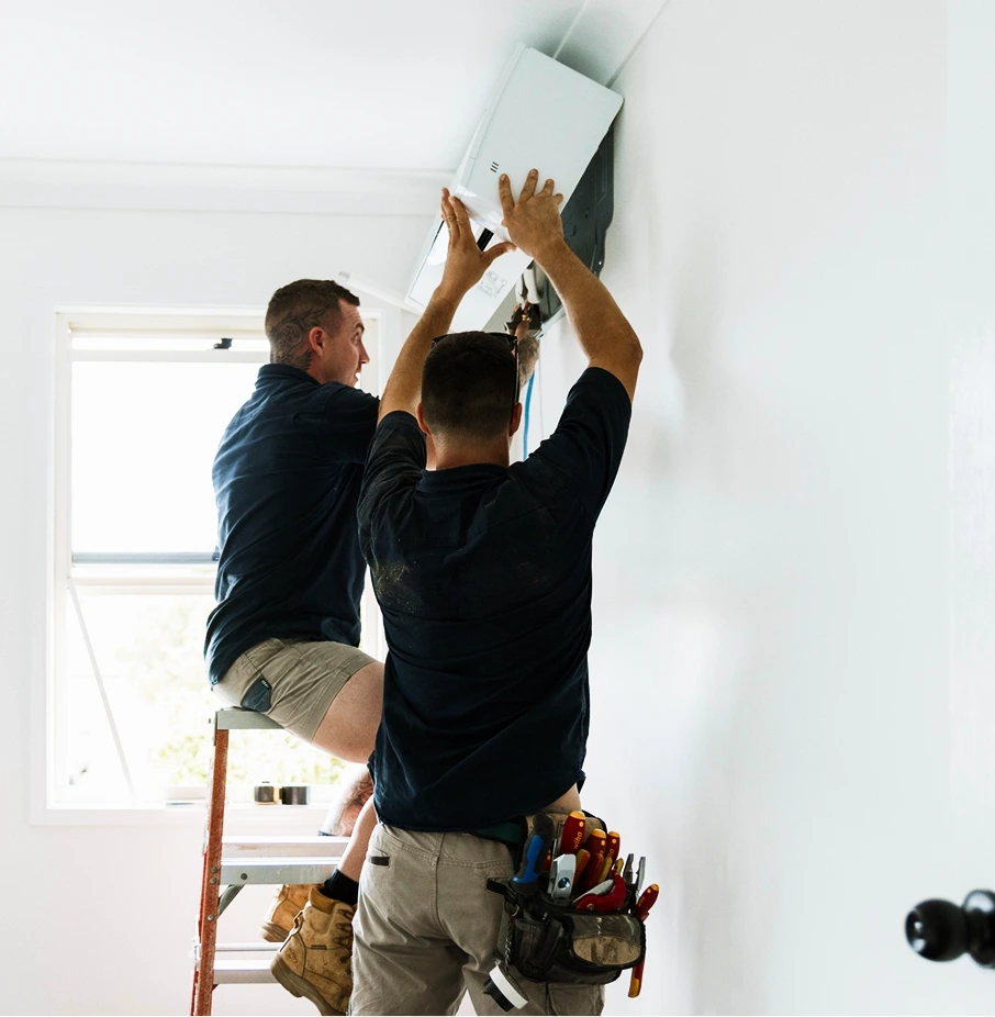Two technicians installing a wall-mounted air conditioning unit, split system installation.