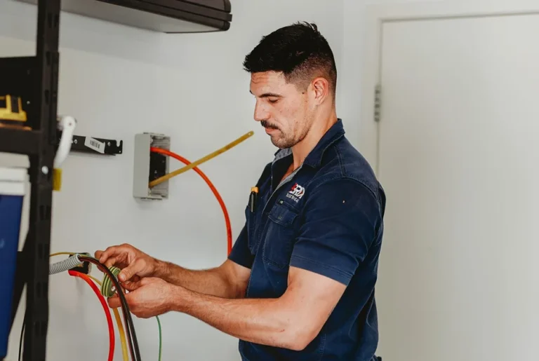 Electrician connecting wiring inside a wall, showing expert installation service.