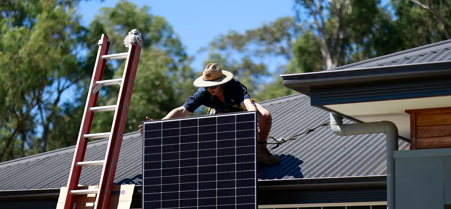 Technician positioning a solar panel on a roof, rooftop panel installation.