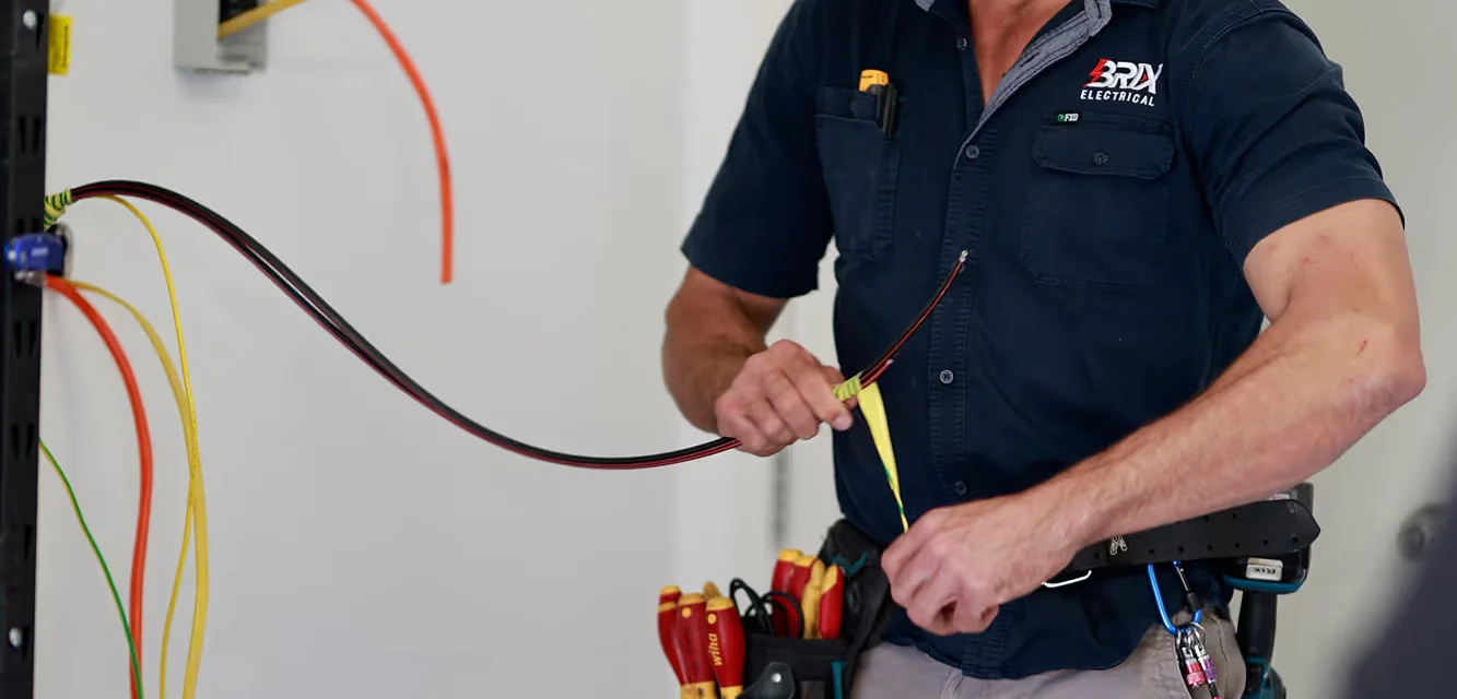 Electrician installing electrical wiring with tools, professional installation work.