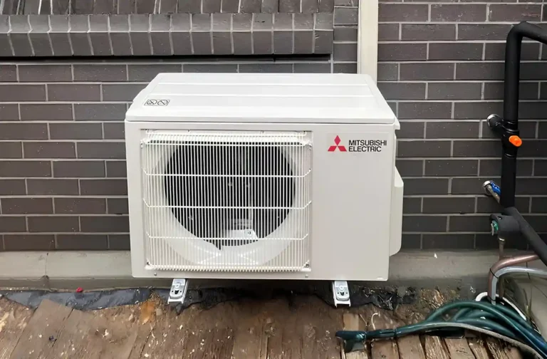 Air conditioning outdoor unit installed beside a house wall, showing outdoor system setup.