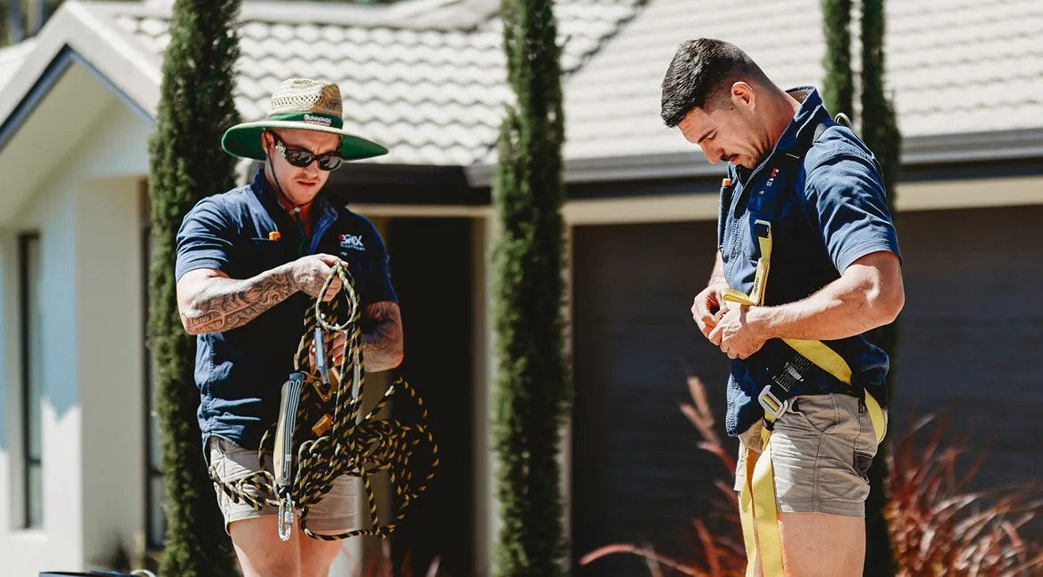 Two Brix Electrical & Air electricians preparing fall protection gear outside a residential property